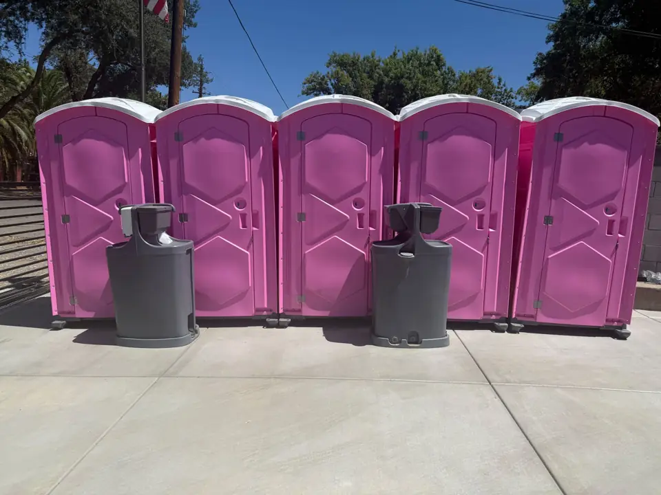 Row of pink porta potties with hand wash stations at an event venue