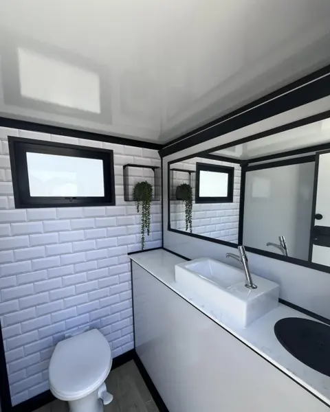 Restroom trailer interior with white tile wall, sink and toilet