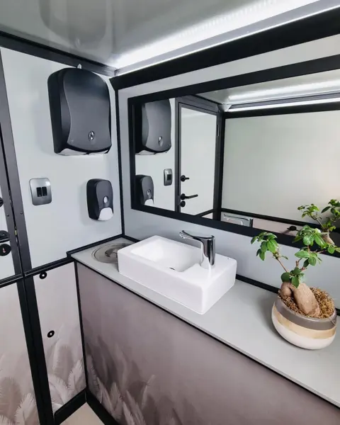 Restroom trailer vanity with sink, mirror, soap and paper towel dispenser